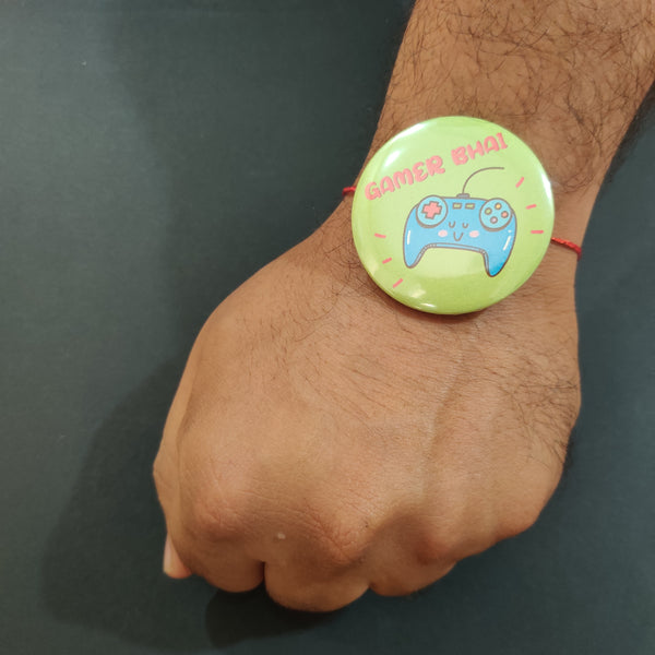 Close-up detail of gaming-themed design or 'Gamer Bhai' inscription on metal Rakhi and magnet.