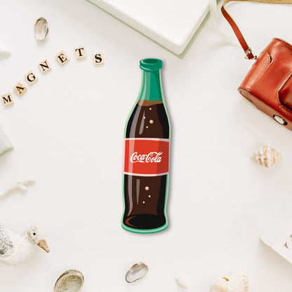 A miniature, classic Coke bottle-shaped fridge magnet with a realistic logo.