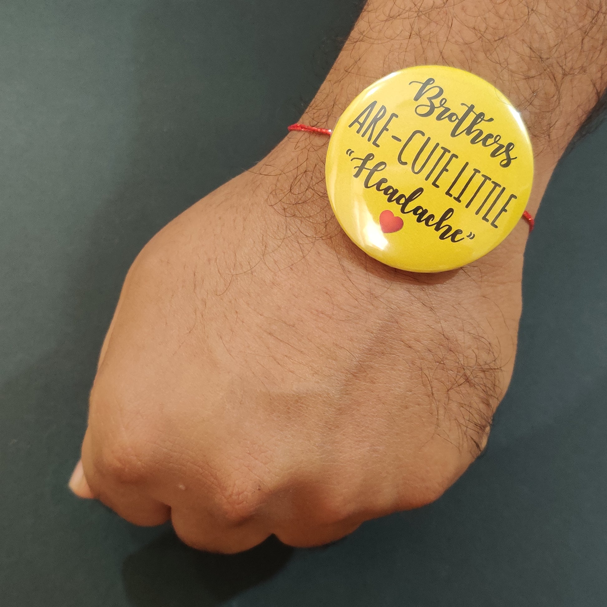 Brothers are Cute Little Headache Rakhi shown both on a thread and as a fridge magnet.