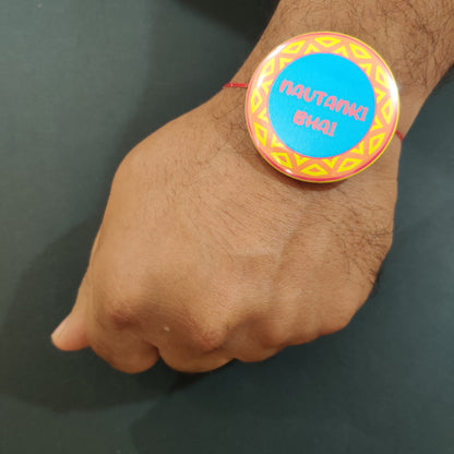 Close-up detail of 'Nautanki Bhai' inscription or theatrical motif on metal Rakhi and magnet