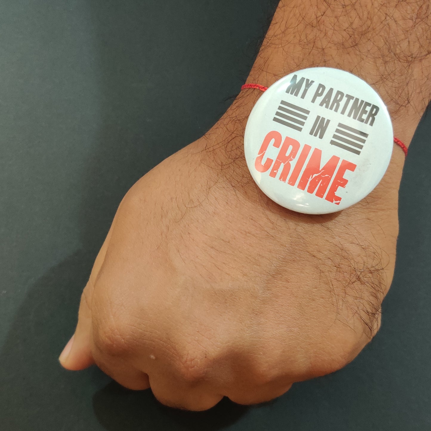 Close-up detail of 'Partner in Crime' inscription on metal Rakhi and magnet.