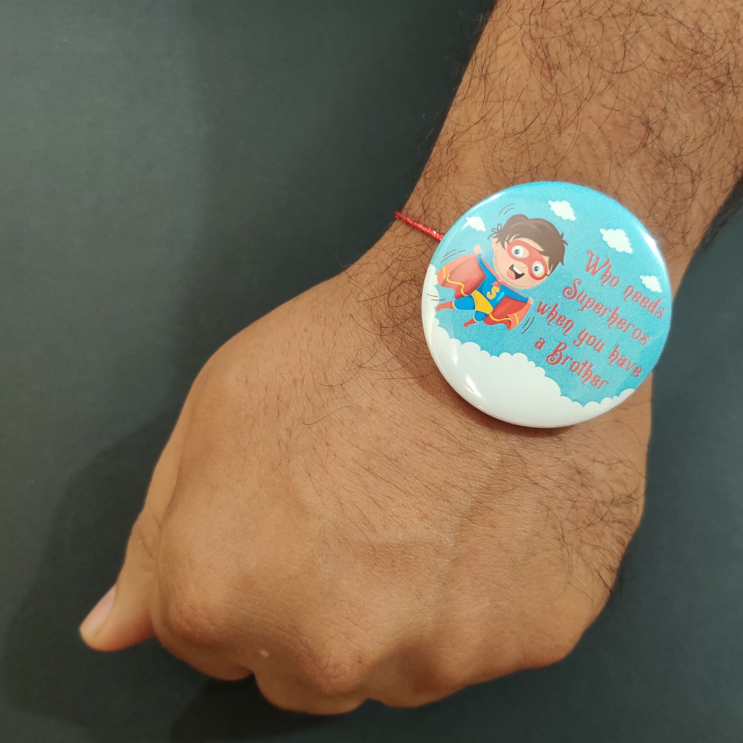 Close-up detail of 'Brother is Superhero' inscription on metal Rakhi and magnet.