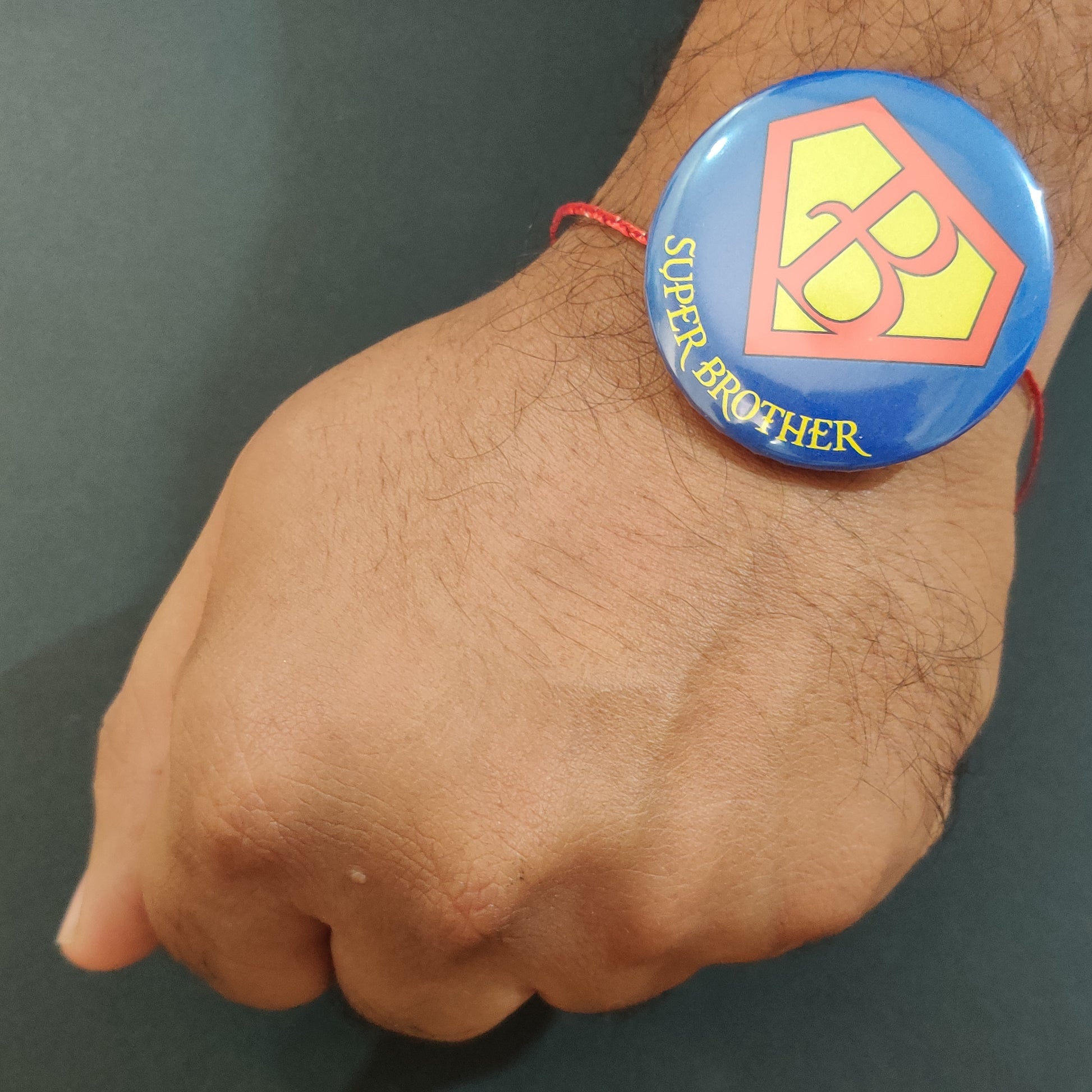 Close-up detail of 'Super Brother' inscription on metal Rakhi and magnet.