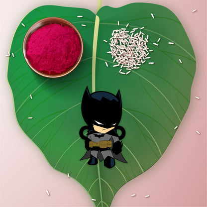 Batman Rakhi with Rudraksha placed against a Gotham City or dark superhero-themed backdrop