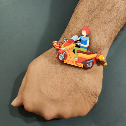 Adventurous brother wearing Biker Bhai Wooden Rakhi with Rudraksha thread on his wrist, perhaps near a motorcycle.