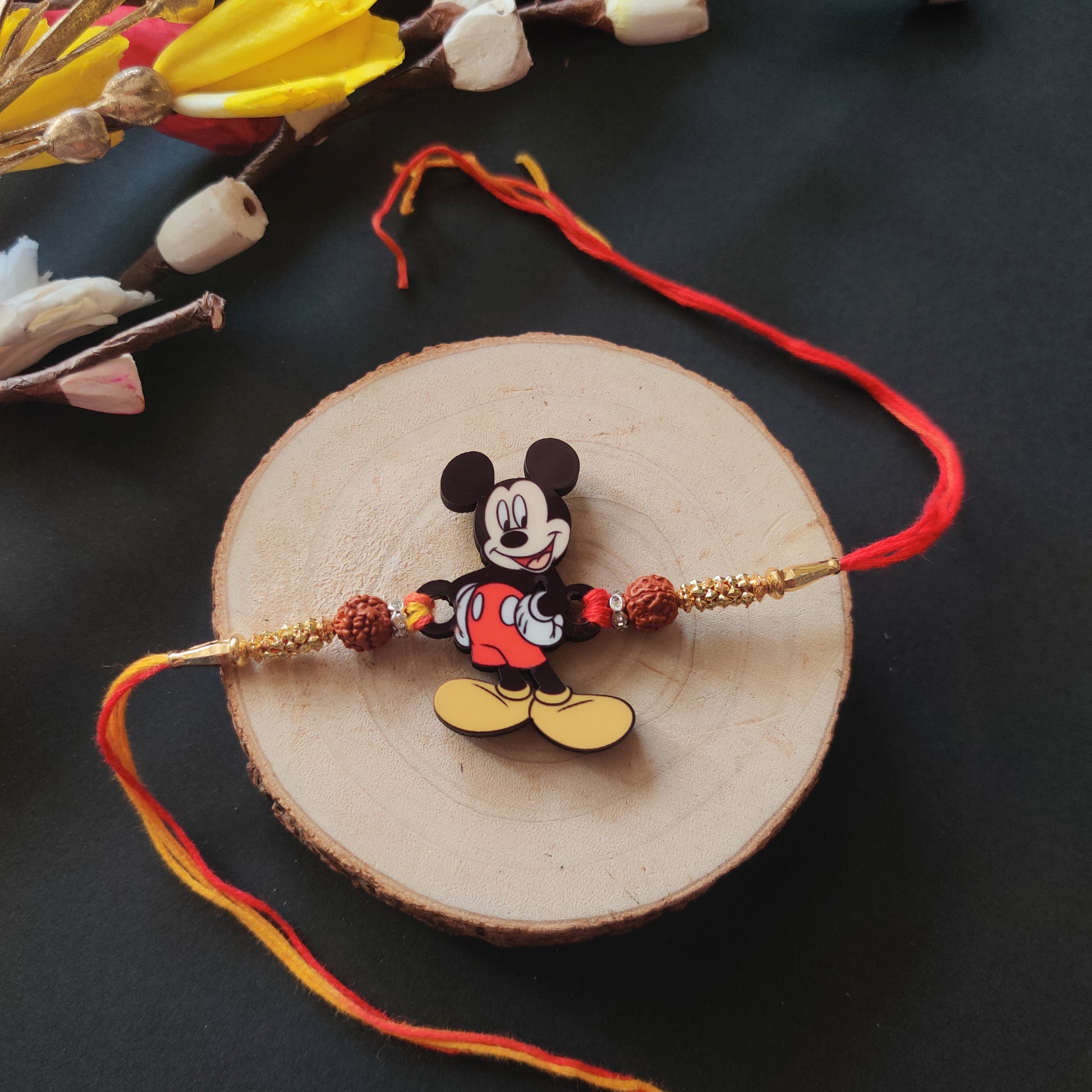 Mickey Wooden Rakhi with Rudraksha thread, presented with Roli and Chawal for Raksha Bandhan.
