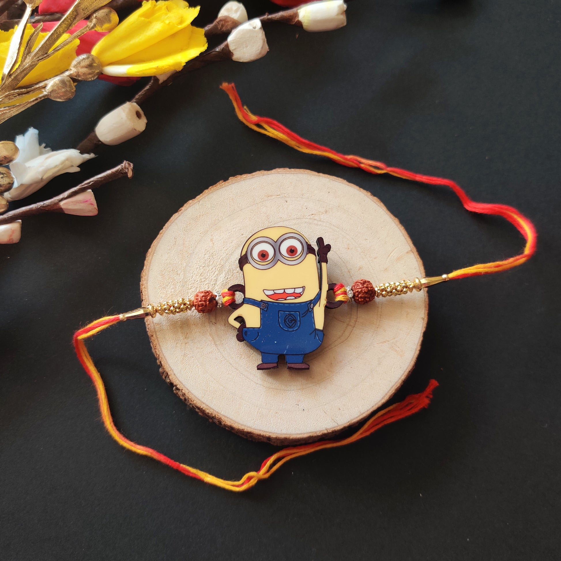 Minion Wooden Rakhi with Rudraksha thread, presented with Roli and Chawal for Raksha Bandhan.