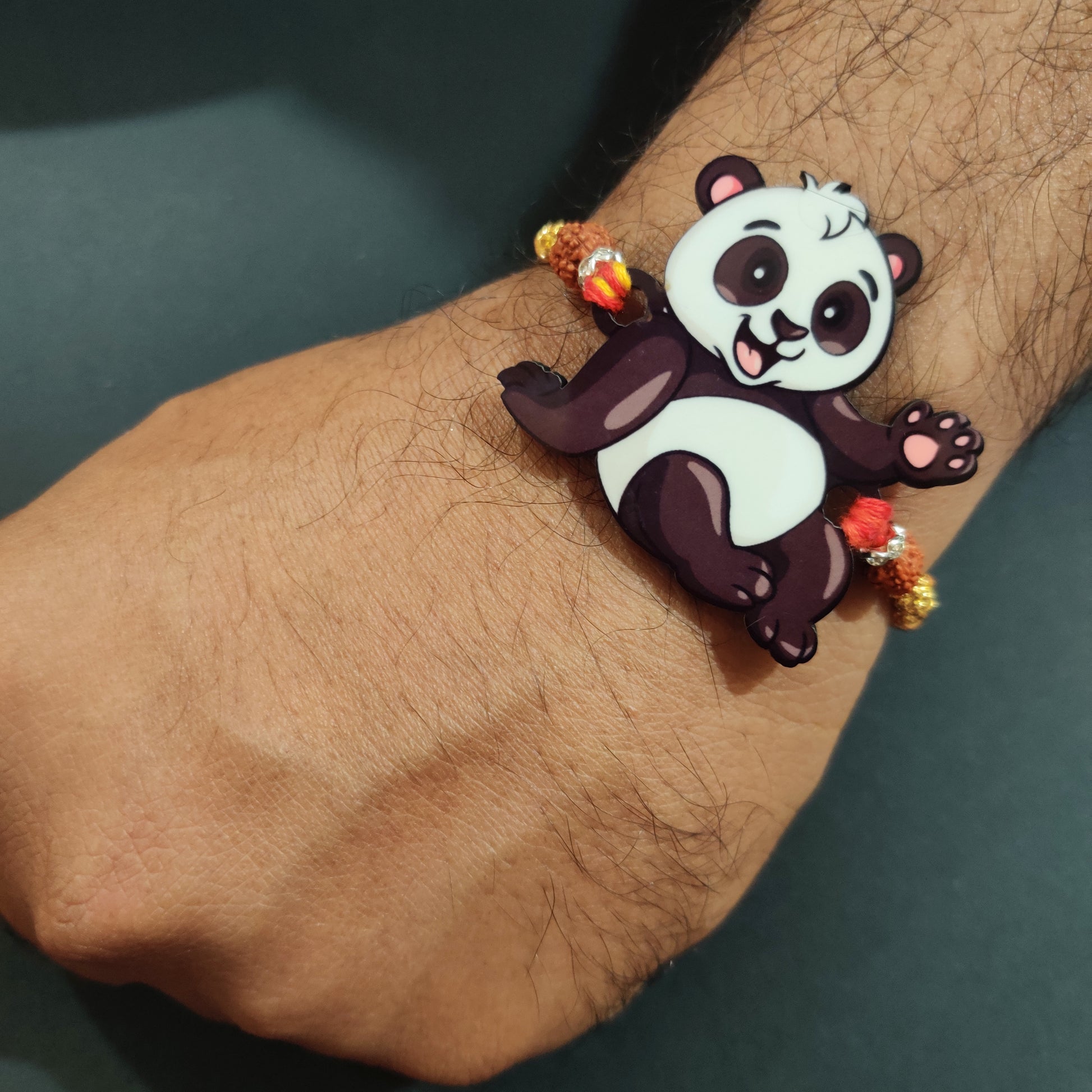 Adorable Panda Wooden Rakhi with Rudraksha thread worn on a brother's wrist.