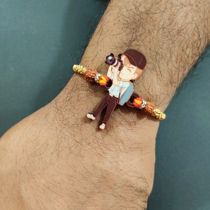 Photographer Bhai Wooden Rakhi with Rudraksha thread worn on a brother's wrist, perhaps holding a camera.