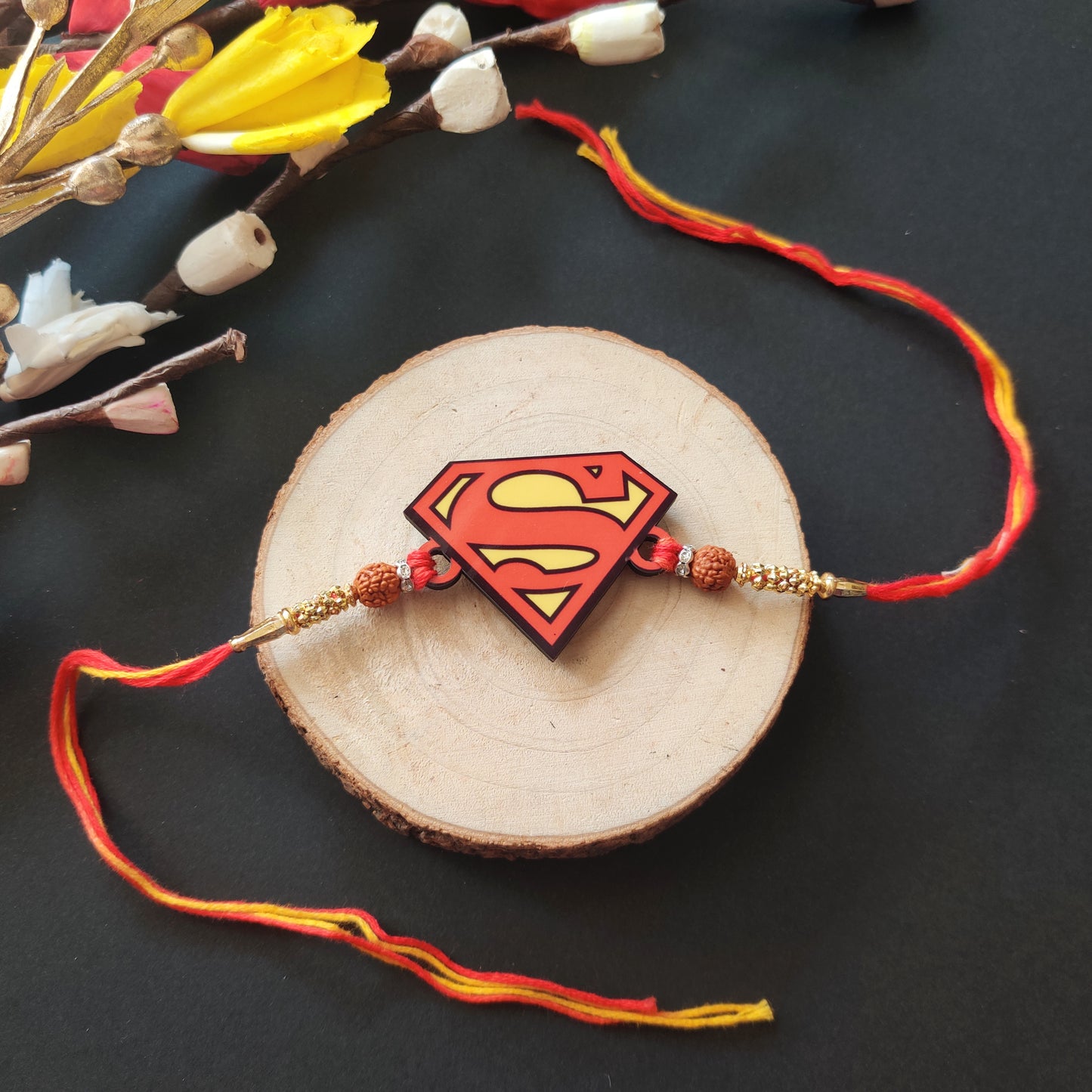 Superman Wooden Rakhi with Rudraksha thread, presented with Roli and Chawal for Raksha Bandhan.